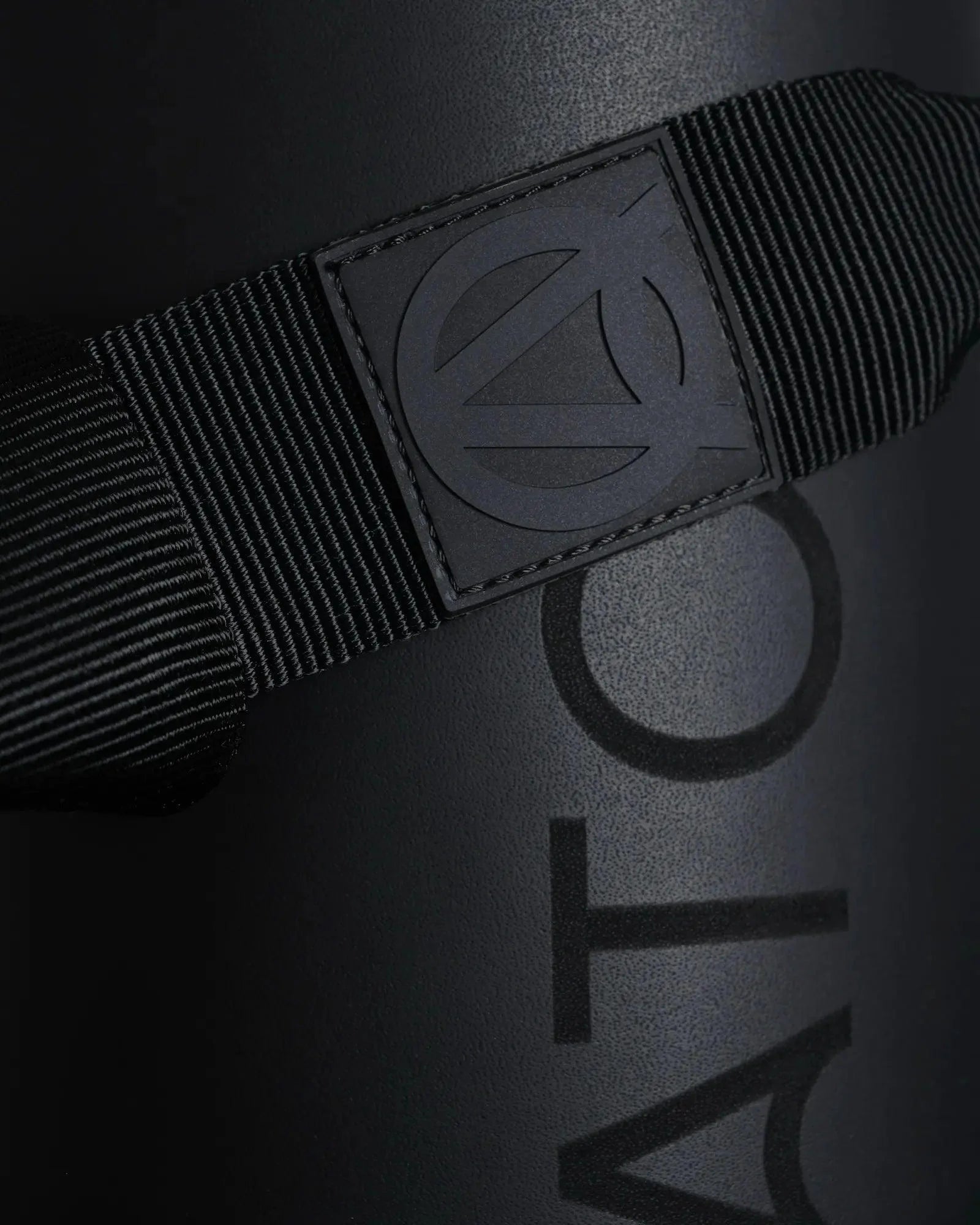 Detailed close-up of a black exercise mat with a black carrying yoga strap