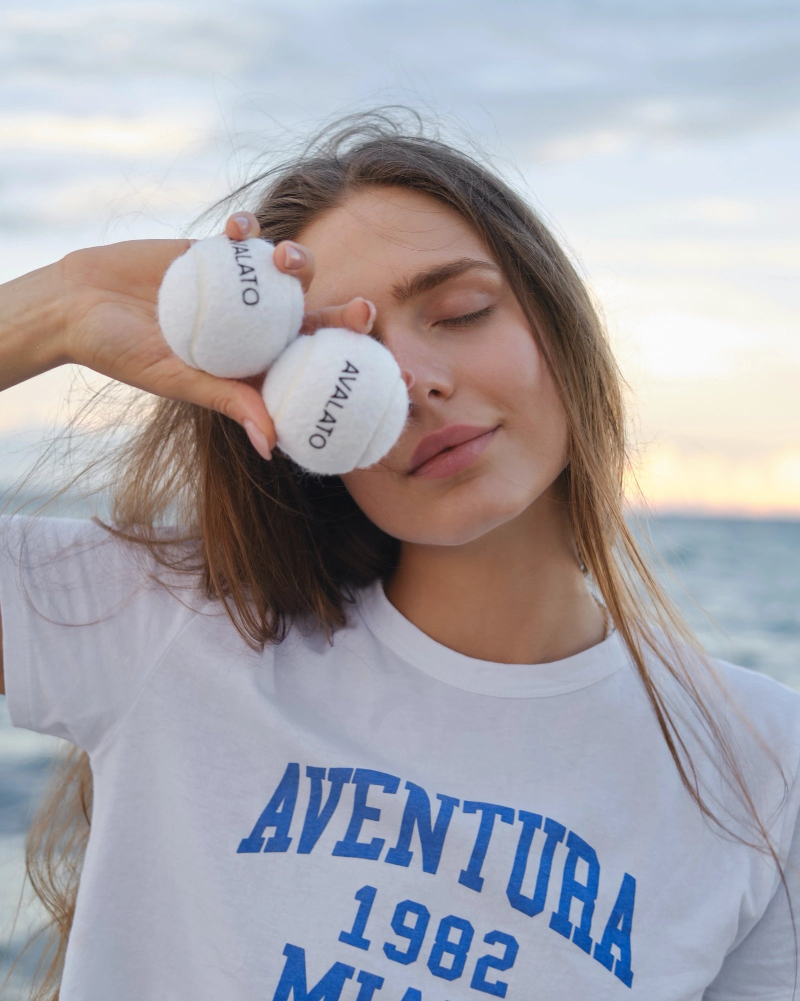 Girl holding white tennis balls on the beach