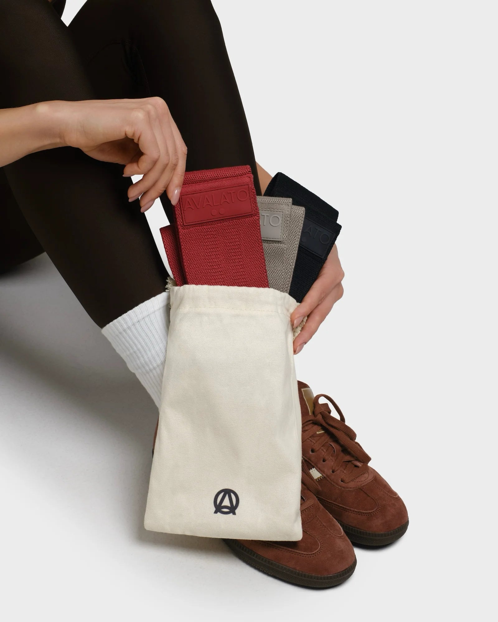 Close-up of a woman holding a beige carrying bag with black, red, and beige resistance bands inside