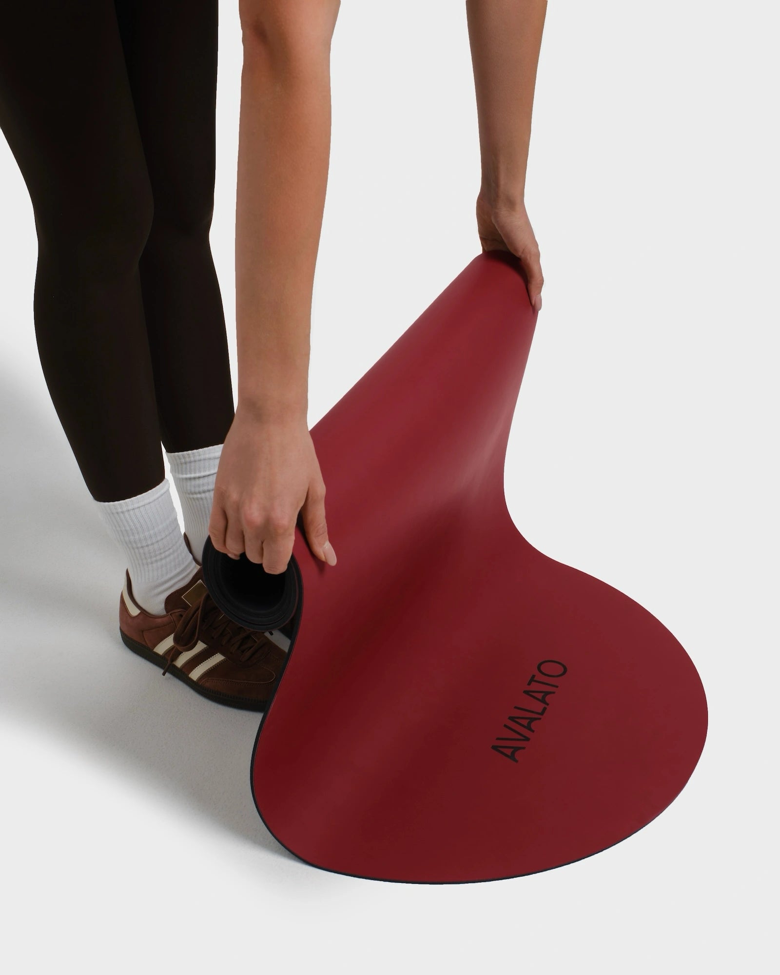 Close-up of a woman rolling up a red avalato exercise mat