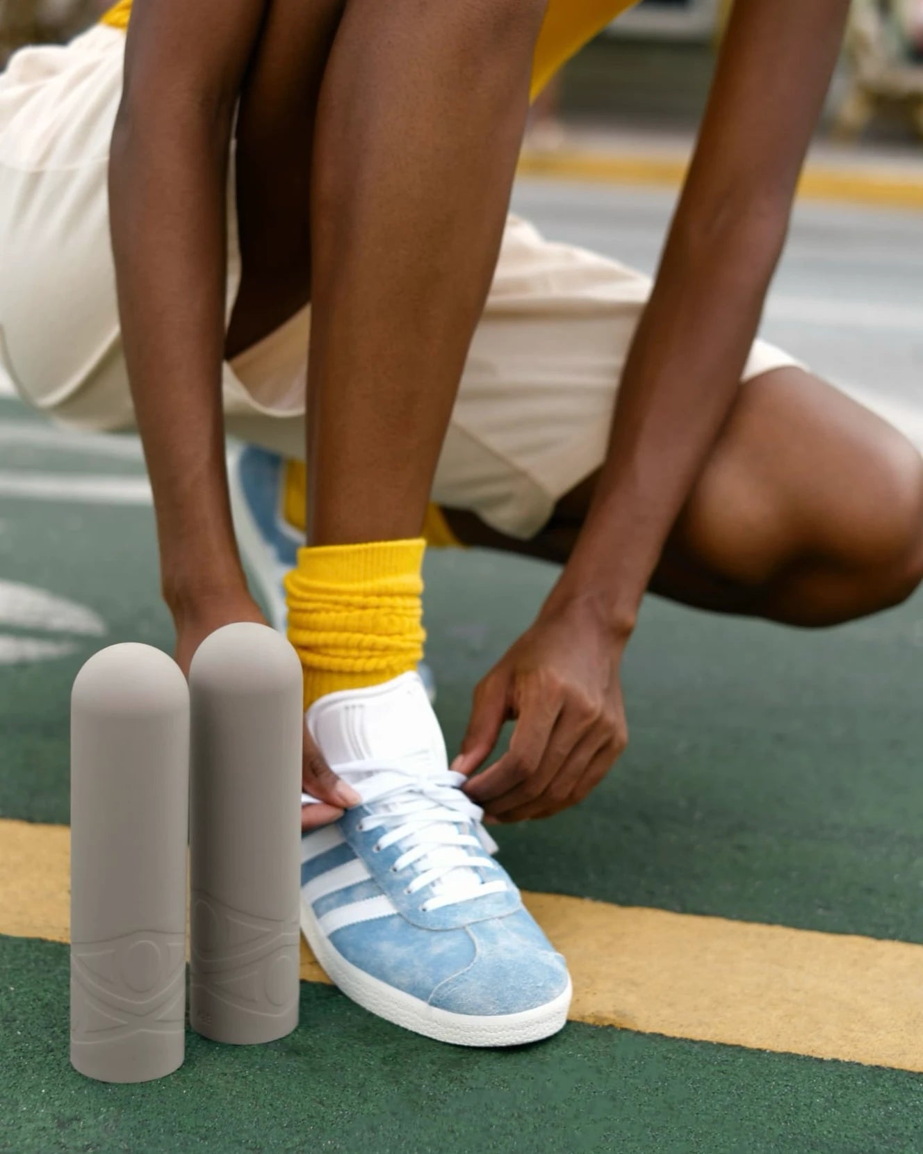 Athletic woman ties sneakers, showcasing workout gear, silicone dumbbells