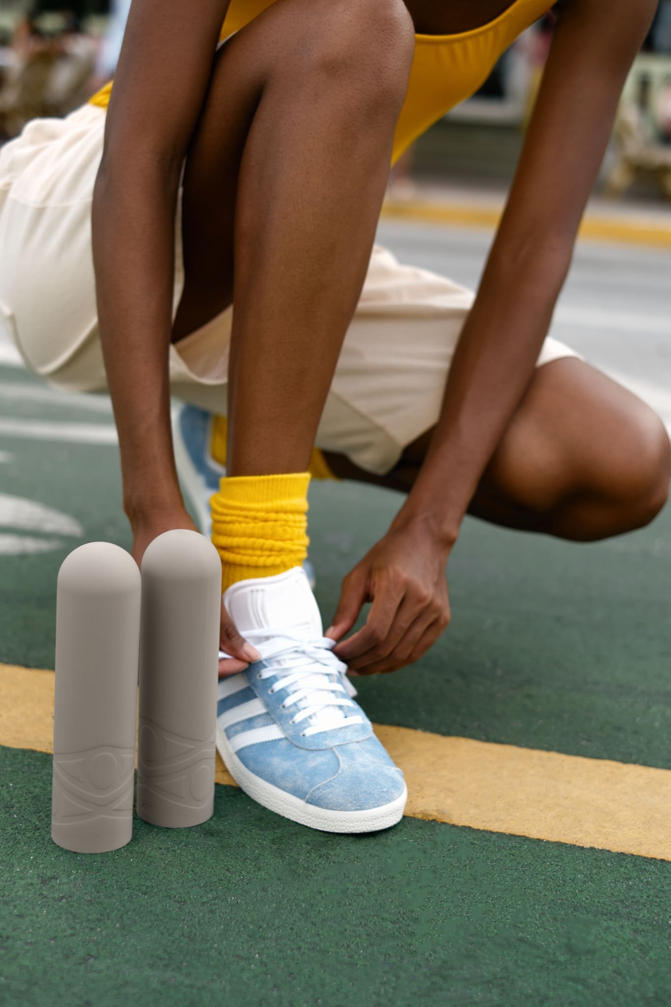 Athletic woman ties sneakers, showcasing workout gear, silicone dumbbells