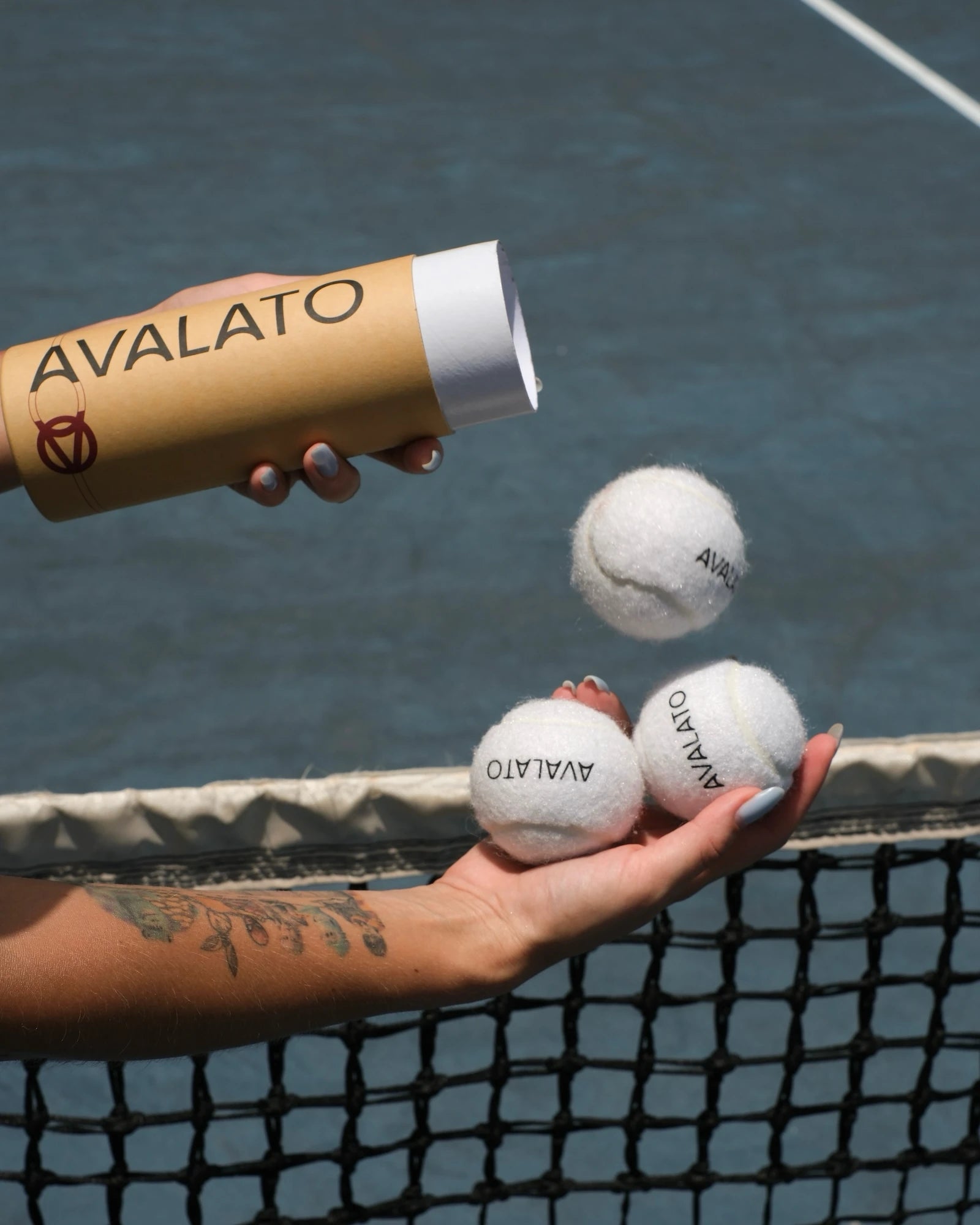 white tennis balls on tennis court falling from kraft tube with tennis net on background