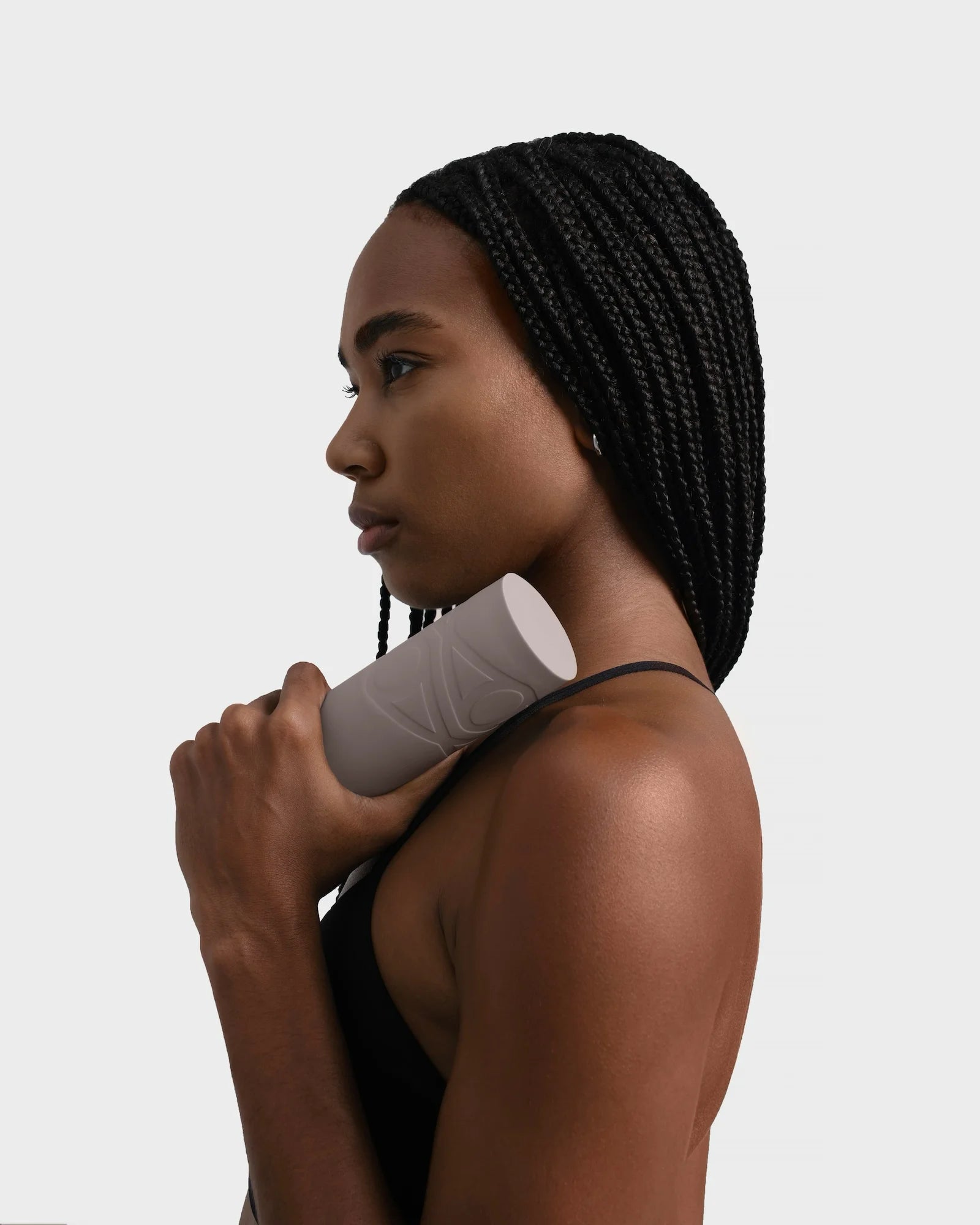 Close-up of a woman in black gym top holding a beige silicone dumbbell